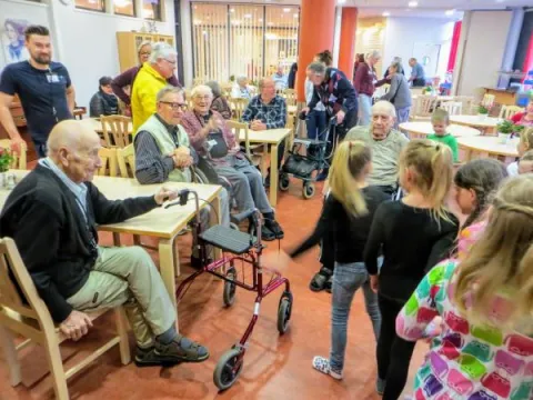 Lapset leikkivät vanhusten edessä.